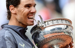 Spain's Rafael Nadal bites the Mousquetaires Cup (The Musketeers) as he poses at the end of the men's singles final match against Austria's Dominic Thiem on day fifteen of The Roland Garros 2019 French Open tennis tournament in Paris on June 9, 2019. PHOTO: PHILIPPE LOPEZ / AFP