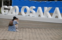A woman takes a picture of a G20 Osaka design set up outside the venue for the G20 Osaka Summit in Osaka on June 26, 2019, ahead of the start of the summit later this week. (Photo by CHARLY TRIBALLEAU / AFP)