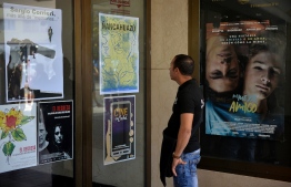 A man looks at posters of films being screened during Cuba's 40th International Film Festival, in Havana on December 7, 2018. - In the good old days, Havana came to a near-standstill for 10 days for its annual film festival, with 500 movies screening in dozens of theatres. On December 6, the 40th edition of the event opened with a vastly reduced budget -- a shadow of what it was in the heady days before the Soviet Union collapsed. (Photo by Yamil LAGE / AFP)