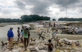 Locals gather concrete fragments and heavy bags wrapped in nets to build a dam as floodwaters flow from the north into the state of Indian eastern state of Bihar near Muzaffarpur on July 13, 2019. - Floods and landslides triggered by torrential monsoon rains have killed at least 40 people across South Asia in the last two days, officials said on July 13. (Photo by STR / AFP)