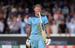 England's Ben Stokes holds his bat in his teeth ahead of a 'super over' during the 2019 Cricket World Cup final between England and New Zealand at Lord's Cricket Ground in London on July 14, 2019. (Photo by Dibyangshu Sarkar / AFP) / 