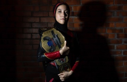 This picture taken on July 6, 2019 shows the hijab-wearing Malaysian wrestler known as Nor "Phoenix" Diana posing for picture with the Wrestlecon championship belt after winning a match against male opponents organised by Malaysia Pro Wrestling in Kuala Lumpur. - A hijab-wearing, diminutive Malaysian wrestler known as "Phoenix" cuts an unusual figure in the ring, a female Muslim fighter taking on hulking opponents in a male-dominated world. (Photo by Mohd RASFAN / AFP) / 