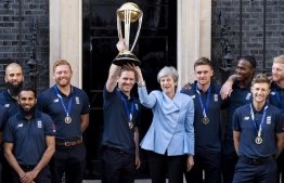 (L-R) England's Moeen Ali, England's Adil Rashid, England's Jonny Bairstow, England's captain Eoin Morgan, Britain's Prime Minister Theresa May, England's Jason Roy, England's Jofra Archer, England's Joe Root and England's Ben Stokes pose for a photograph outside 10 Downing Street with the World Cup trophy as England players arrive for a reception in London on July 15, 2019, a day after they won the 2019 Cricket World Cup after beating New Zealand the final at Lord's. (Photo by Niklas HALLE'N / AFP)