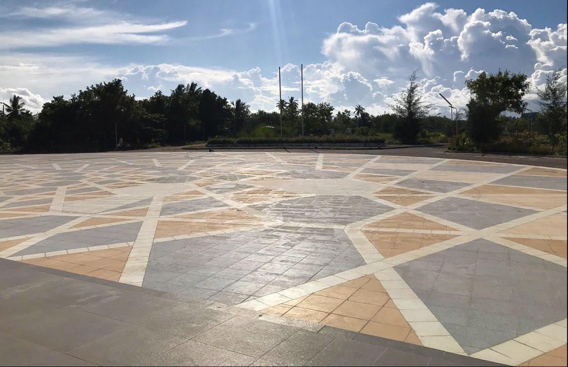 އައްޑޫ އާ ހޮސްޕިޓަލްގެ އެތެރޭގެ ކޮޓަރިއަކުން، އެ ހޮސްޕިޓަލްގެ މައި ގޭޓު ސަރަހައްދު ފެންނަ ގޮތް: މި އިމާރާތުގެ ވަށައިގެންވާ ސަރަހައްދުގެ ލޭންޑް ސްކޭޕިން އަށް ފަހުން ބަދަލުތަކެއް ގެންނާނެ.---ފޮޓޯ: މިހާރު