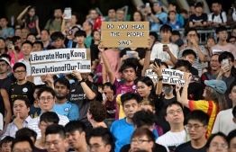Protesters hold up signs related to the recent political events and demonstrations in the territory, during the first half of the friendly football match between English Premier League club Manchester City and Hong Kong side Kitchee at Hong Kong Stadium on July 24, 2019. (Photo by Anthony WALLACE / AFP)