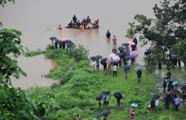 Indian passengers rescued from a train stranded in flood waters walk up a hill to dry land between Badlapur and Vangani following heavy monsoon rains, some 60 kms from Mumbai, on July 27, 2019. - Indian navy helicopters and emergency service boats came to the rescue of about 700 people stuck on a train caught in floods near Mumbai on July 27. (Photo by STR / AFP)