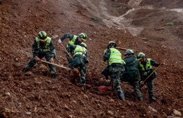 This photo taken on July 25, 2019 shows rescuers searching for survivors at the site of a landslide in Liupanshui in China's southwestern Guizhou province. - The death toll in a landslide that buried a village in southwest China rose to 20 on July 26, with 25 people still missing three days after the disaster, state media said. (Photo by STR / AFP) / 