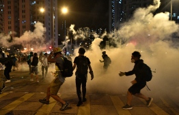 Protesters gather amid tear gas, outside of a police station in the Wong Tai Sin district of Hong Kong early on August 4, 2019, after arrested protesters were taken to the station in a police van. - Anti-government protesters in Hong Kong erected barricades in a popular shopping district and blocked a major tunnel on the evening of  August 3, defying increasingly stern warnings from China over weeks-long unrest that has plunged the city into crisis. (Photo by Anthony WALLACE / AFP)