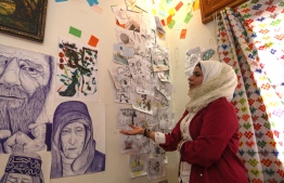 Syrian Cartoonist Amani al-Ali speaks about some of her drawings at her home studio in the city of Idlib in the eponymous northwestern province, on June 16, 2019. In war-torn northwest Syria, cartoonist Amani al-Ali takes her pen to the screen to sketch life in the embattled opposition bastion of Idlib. Through her cartoons, Ali has boldly challenged traditions to comment on life in the anti-regime bastion, and to condemn seeming international indifference to civilian deaths. PHOTO: Omar HAJ KADOUR / AFP