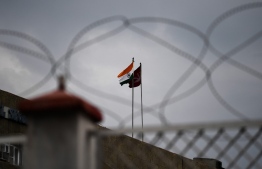 In this picture taken on August 6, 2019 an Indian national flag flies next to a Jammu and Kashmiri flag ontop of a building during a curfew in Srinagar on August 6, 2019. (Photo by Sajjad HUSSAIN / AFP)