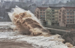 Waves hit a sea wall in front of buildings in Taizhou, China's eastern Zhejiang province on August 9, 2019. - China issued a red alert for incoming Super Typhoon Lekima which is expected to batter eastern Zhejiang province early on August 10 with high winds and torrential rainfall. (Photo by - / AFP) / 