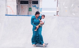 A mother skateboarding in traditional 'Dhigu Hedhun' while holding her son, wearing 'Feyli' and a white shirt. PHOTO: IYAD IBRAHIM