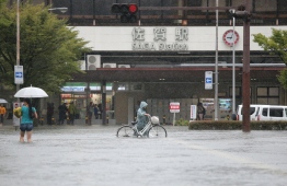 Pedestrians walk in floodwaters after heavy rains outside Saga station in the southwestern city of Saga on August 28, 2019. - Japanese authorities on August 28 issued a rare evacuation order for 240,000 people in the country's southwest over flood and landslide fears, as officials confirmed a man was killed in heavy rains. (Photo by JIJI PRESS / JIJI PRESS / AFP) / 