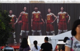 People walk past photos of China's basketball team players on the wall of the Cadillac Arena, one of the venues for the Basketball World Cup, in Beijing on August 29, 2019. - The Basketball World Cup will be played in eight cities across China, starting on August 31. (Photo by GREG BAKER / AFP)