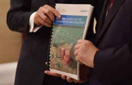 Former UN head Ban Ki-moon (R) and Patrick Verkooijen, CEO of the Global Center on Adaptation, pose with a report on climate adaptation in Beijing on September 10, 2019. - Nations rich and poor must invest now to protect against the impact of climate change -- or pay an even heavier price later, a global commission led by former UN head Ban Ki-moon warns. (Photo by GREG BAKER / AFP)