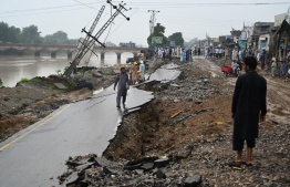 People stand on a damaged road in an earthquake-hit area on the outskirts of Mirpur on September 25, 2019. - Rescue workers battled on September 25 to reach people affected by a shallow earthquake that rocked northeast Pakistan a day earlier, killing at least 22 people and injuring hundreds more as it tore roads apart and felled buildings. (Photo by AAMIR QURESHI / AFP)