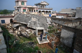 Pakistani residents look at a collapsed house in an earthquake-hit area on the outskirts of Mirpur in Pakistan-controlled Kashmir on September 25, 2019. - Rescuers battled along badly damaged roads and combed through toppled buildings September 25 to reach victims of an earthquake that killed at least 25 people and injured hundreds more in northeast Pakistan. (Photo by AAMIR QURESHI / AFP)