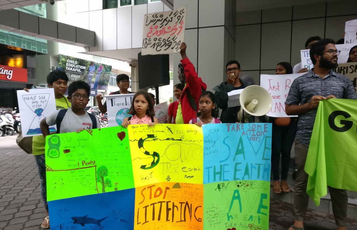 މާލެ: ސެޕްޓެމްބަރު 26، 2019: ތިމާވެއްޓަށް ދޭ ގެއްލުންތަކުން ދުނިޔެ ސަލާމަތް ކުރުމަށް ގޮވާލައި ކުރަމުންދާ ހަޅުތާލުގައި ބައިވެރިވި ކުދިންތަކެއް ތިމާވެށި ހިމާޔަތް ކޮށްދިނުމަށް ގޮވާލާ ހަދާފައިވާ ބޯޑްތަކެއް ހިފައިގެން.-- ފޮޓޯ: ސޭވް މޯލްޑިވްސް