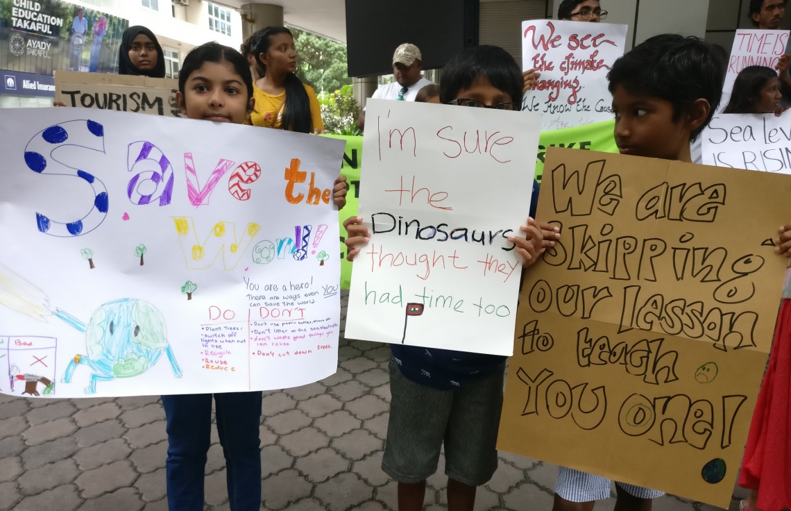 މާލެ: ސެޕްޓެމްބަރު 26، 2019: ތިމާވެއްޓަށް ދޭ ގެއްލުންތަކުން ދުނިޔެ ސަލާމަތް ކުރުމަށް ގޮވާލައި ކުރަމުންދާ ހަޅުތާލުގައި ބައިވެރިވި ކުދިންތަކެއް ތިމާވެށި ހިމާޔަތް ކޮށްދިނުމަށް ގޮވާލާ ހަދާފައިވާ ބޯޑްތަކެއް ހިފައިގެން.-- ފޮޓޯ: ސޭވް މޯލްޑިވްސް