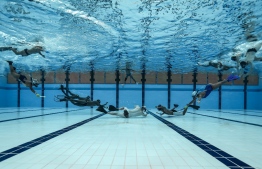 This picture taken on August 26, 2019 shows players fighting for the puck during an underwater hockey training session ahead of the Southeast Asian (SEA) Games in the Philippines later this year, at the National Aquatic Centre in Bukit Jalil, on the outskirts of Kuala Lumpur. - Invented in the 1950s in Britain -- where it is known as "Octopush" -- to help divers keep fit during the winter months, the game has gained a small but dedicated following from Europe to Asia. This year the unusual discipline is set to debut at the Southeast Asian Games, the region's biennial mini-Olympics that attracts thousands of athletes. (Photo by Mohd RASFAN / AFP) / 