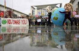 Environmentalists hold a banner reading "How dare you", quoting Swedish teenage climate activist Greta Thunberg, and wear masks of German Chancellor Angela Merkel and Finance Minister and Vice-Chancellor Olaf Scholz as they protest outside the German Chancellery where is taking place the weekly cabinet meeting in Berlin on September 25, 2019. (Photo by Tobias SCHWARZ / AFP)