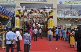 In this photograph taken on September 28, 2019, customers stand out of a shopping mall  which is decorated for upcoming Hindu 'Dushhera-Vijaya Dashami' festival, marking the end of 'Durga Puja' that honors goddess Durga's victory, in Hyderabad. - E-commerce giants Amazon and Walmart-backed Flipkart kicked off a crucial battle for shoppers on Sunday ahead of India's massive festive season as retailers search for a much-needed boost to sales in a slowing economy. (Photo by NOAH SEELAM / AFP) / 