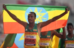 Ethiopia's Muktar Edris celebrates with the national flag after winning in the Men's 5000m final at the 2019 IAAF Athletics World Championships at the Khalifa International Stadium in Doha on September 30, 2019. (Photo by Jewel SAMAD / AFP)