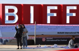 (FILES) In a file photo taken on October 13, 2017, visitors take a selfie in front of logo for the 22nd Busan International Film Festival (BIFF), at Haeundae beach in Busan. - Organisers of Asia's top film festival, which opens in Busan October 3, 2019, warn that a surge of global interest in the critically acclaimed South Korean movie "Parasite" masks a damaging underinvestment in local independent cinema. (Photo by Jung Yeon-je / AFP) / TO GO WITH SKorea-entertainment-festival-film,ADVANCER by Matthew SCOTT