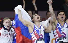 Russia's Artur Dalaloyan (R) and David Belyavskiy (C) react after they won the men‘s team final at the FIG Artistic Gymnastics World Championships PHOTO: THOMAS KIENZLE / AFP