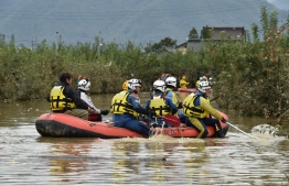 Emergency personnel paddle across floodwaters using an inflatable raft during search and rescue operations in the aftermath of Typhoon Hagibis, in Nagano on October 14, 2019. - Tens of thousands of rescue workers were searching October 14 for survivors of powerful Typhoon Hagibis, two days after the storm slammed into Japan, killing at least 35 people. (Photo by Kazuhiro NOGI / AFP)