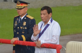 (FILES) This file photo taken on August 8, 2018 shows Philippine President Rodrigo Duterte (R) reviewing policemen along with national police chief Oscar Albayalde (L) in a sudden downpour during the 117th police anniversary celebration at the national headquarters in Manila. - The Philippines' top policeman Oscar Albayalde, who leads the nation's deadly drugs crackdown, quit on October 14, 2019 as he faces accusations of protecting officers who allegedly sold a huge haul of seized narcotics. (Photo by Ted ALJIBE / AFP)