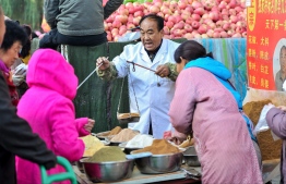 This photo taken on October 15, 2019 shows a vendor (C) selling spices at a market in Shenyang in China's northeastern Liaoning province. - China's economy expanded at its slowest rate in nearly three decades during the third quarter 2019, held back by cooling domestic demand and a protracted US trade war, according to an AFP survey of analysts on October 16. (Photo by STR / AFP) / 