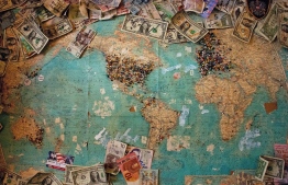 Foreign currency notes on a world map. PHOTO: CHRISTINE ROY / UNSPLASH