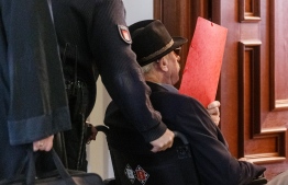 93-year-old former SS guard Bruno Dey covers his face as he arrives at the courtroom in Hamburg, on October 17, 2019. - Dey stands accused of involvement in the murder of 5,230 people when he worked at the Stutthof camp near what was then Danzig, now Gdansk in Poland. (Photo by Markus Scholz / POOL / AFP)