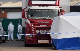 Police officers in a forsensic suits are photographed at the scene with a lorry, believed to have originated from Bulgaria, and found to be containing 39 dead bodies, inside a police cordon after being discovered at Waterglade Industrial Park in Grays, east of London, on October 23, 2019. - British police said 39 bodies were found near London Wednesday in the container of a truck thought to have come from Bulgaria. Essex Police said the people were all pronounced dead at the scene in an industrial park in Grays, east of London. Early indications suggest the victims are 38 adults and one teenager. A 25-year-old man from Northern Ireland has been arrested on suspicion of murder. (Photo by Ben STANSALL / AFP)