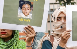 (FILES) In this file photo taken on April 12, 2019 women hold placards with a photograph of schoolgirl Nusrat Jahan Rafi at a protest in Dhaka, following her murder by being set on fire after she had reported a sexual assault. - A court in Bangladesh sentenced 16 people to death on October 24 over the murder of a 19-year-old female student burnt alive in April that provoked outrage across the country. (Photo by SAZZAD HOSSAIN / AFP)