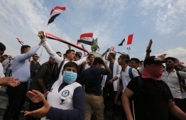 Iraqi students wave the national flag during an anti-government protest in the capital's Nusur square, on October 27, 2019. - The Iraqi capital and south have been rocked by a second wave of demonstrations since October 24, with protesters persevering despite tear gas, curfews and violence that has left over 60 dead. (Photo by - / AFP)