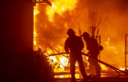 Firefighters battle a wind-driven fire burning structures on a farm during the Kincade fire in Windsor, California on October 27, 2019. - California's governor declared a state-wide emergency on October 27 as a huge wind-fueled blaze forced evacuations and massive power blackouts, threatening towns in the famed Sonoma wine region. (Photo by Philip Pacheco / AFP)