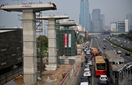 Vehicles commute next to a construction site of the LRT (light rapid transit) in Jakarta on October 31, 2019. (Photo by BAY ISMOYO / AFP)