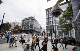 (FILES) In this file photo taken on August 16, 2019 People walk past a CCTV camera operating on Oxford Street in Londo. - The experiment was conducted discreetly. Between 2016 and 2018, two surveillance cameras were installed in the Kings Cross area of London to analyse and track passers-by using facial recognition technology. (Photo by Tolga Akmen / AFP)