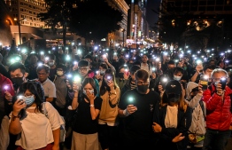 People hold their mobile phones as they gather to pray for the students who are barricaded inside Hong Kong Polytechnic University campus at Salisbury garden in Tsim Sha Tsui district of Hong Kong on November 19, 2019. - A dwindling number of exhausted pro-democracy protesters barricaded inside the Hong Kong university defied warnings on November 19 to surrender, as a police siege of the campus stretched through a third day and China sent fresh signals that its patience with nearly six months of unrest was running out. (Photo by YE AUNG THU / AFP)