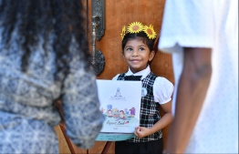 A pre-school student receives her report card on Thursday. PHOTO: HUSSAIN WAHEED / MIHAARU