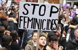 A person holds up a placard reading " stop feminicide " during a protest at the International day for elimination of violence against women in Paris, on November 23, 2019. (Photo by DOMINIQUE FAGET / AFP)