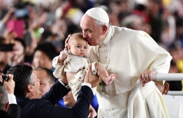 Pope Francis kisses a young child upon his arrival for a holy mass at the Tokyo Dome stadium in Tokyo on November 25, 2019. - Pope Francis called on November 25 for renewed efforts to help victims of Japan's 2011 "triple disaster" of earthquake, tsunami and the Fukushima meltdown, noting "concern" in the country over the continued use of nuclear power. (Photo by Vincenzo PINTO / AFP)