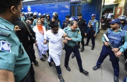 Police escort detainees (C) accused of allegedly plotting the Holey Artisan Bakery cafe attack, carried out by Islamist militants, to a courtroom for their trial in Dhaka on November 27, 2019. - Five young men armed with guns and knives stormed the cafe on July 1, 2016 taking dozens hostage and killing 22 people. (Photo by Munir UZ ZAMAN / AFP)