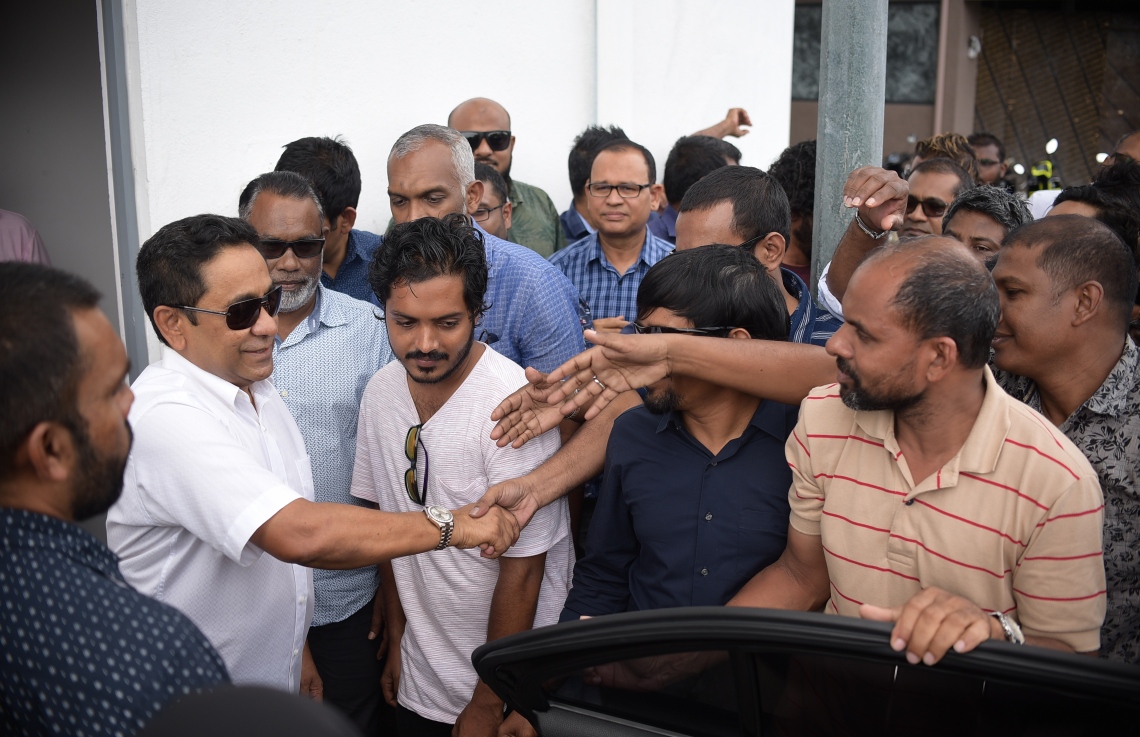 މާލެ: ނޮވެމްބަރު 28، 2019: ކުރީގެ ރައީސް ޔާމީނަށް ހުކުމް އިއްވުމުގެ ޝަރީއަތަށް ކްރިމިނަލް ކޯޓަށް ވަޑައިގަތުމުގެ ކުރިން އެމަނިކުފާނުގެ ސަޕޯޓަރުންނާ ސަލާމް ކުރައްވަނީ.---ފޮޓޯ: ނިޝާން އަލީ/މިހާރު