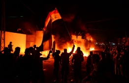 Iraqi demonstrators gather as flames start consuming Iran's consulate in the southern Iraqi Shiite holy city of Najaf on November 27, 2019, two months into the country's most serious social crisis in decades. - Iraqi protesters torched the Iranian consulate in the holy city of Najaf in a dramatic escalation of anti-government demonstrations that have left more than 350 people dead. (Photo by Haidar HAMDANI / AFP)