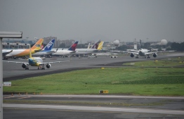 Passenger planes are parked while others taxi at the departure building of Manila international airport on December 3, 2019, hours before the deadline of the closure of the airport due to Typhoon Kamurri. - Typhoon Kammuri lashed the Philippines with fierce winds and heavy rain, as hundreds of thousands took refuge in shelters and the capital Manila prepared to shut down its international airport over safety concerns. (Photo by Ted ALJIBE / AFP)