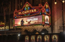 (FILES) In this file photo taken on November 13, 2019 The marquee of El Capitan theatre in Hollywood for Disney+ World Premiere of "The Mandalorian". - Baby Yoda may stand only a few inches tall, communicating with high-pitched squeaks and mischievous gestures, but the adorable green creature looms large online, causing a global social media meltdown. The cute, wide-eyed tyke, unveiled three weeks ago in the premiere of Disney's live-action Star Wars series "The Mandalorian", has stolen both the show and millions of hearts. (Photo by Nick Agro / AFP)