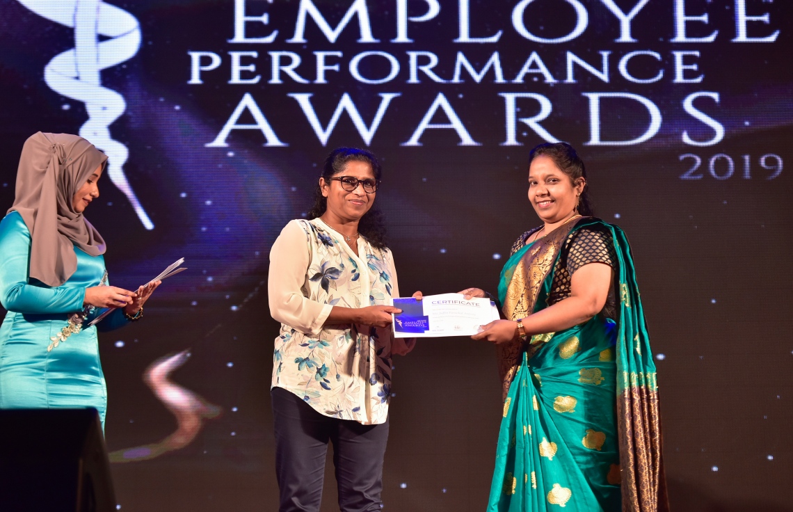 މާލެ- ޑިސެމްބަރު 8، 2019: އޭޑީކޭ ހޮސްޕިޓަލްގެ މުވައްޒަފުންގެ އަގު ވަޒަން ކުރަން ބޭއްވި ހަފްލާގައި އެހޮސްޕިޓަލްގެ މިދިޔަ އަހަރު ޕާފޯމަންސް އެވޯޑު ލިބުނު މުވައްޒަފަކާ އިނާމު ހަވާލު ކުރައްވަނީ --. ފޮޓޯ: ނިޝާން އަލީ/ މިހާރު